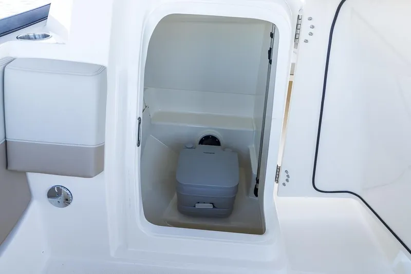 Slide: The Image of Open storage compartment on 2026 Boston Whaler 210 Vantage boat with red bucket inside. - 15