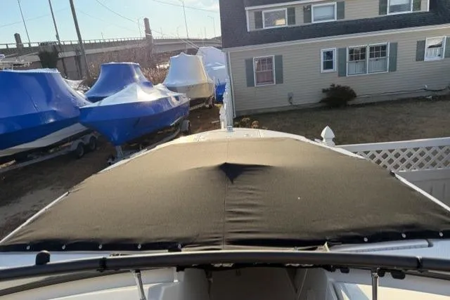 Slide: The Image of 2026 Boston Whaler 210 Vantage boat with cover, parked near a house. - 25