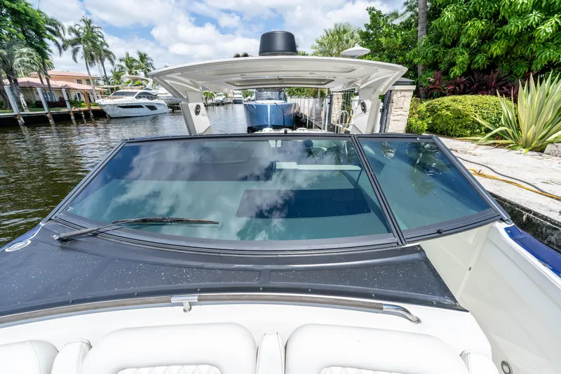 Slide: The Image of 2019 Sea Ray SLX 400 Outboard boat docked by lush greenery and waterfront homes. - 45