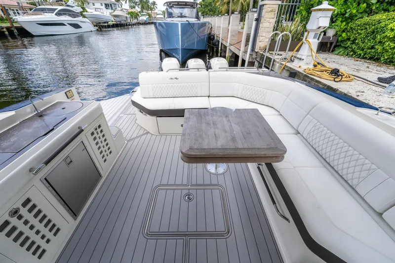 Slide: The Image of 2019 Sea Ray SLX 400 Outboard interior with elegant seating and table, docked by waterfront. - 57