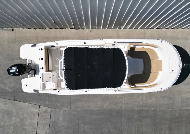 Slide: The Image of 2023 Bayliner Trophy T24CC boat, aerial view, docked, with black cover and outboard motor. - 23