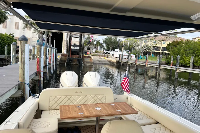 Slide: The Image of 2023 Chris-Craft Calypso 30 boat docked, featuring elegant seating and dual outboard engines. - 11