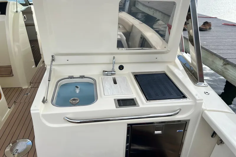 Slide: The Image of 2023 Chris-Craft Calypso 30 boat kitchen area with sink, grill, and storage. - 12