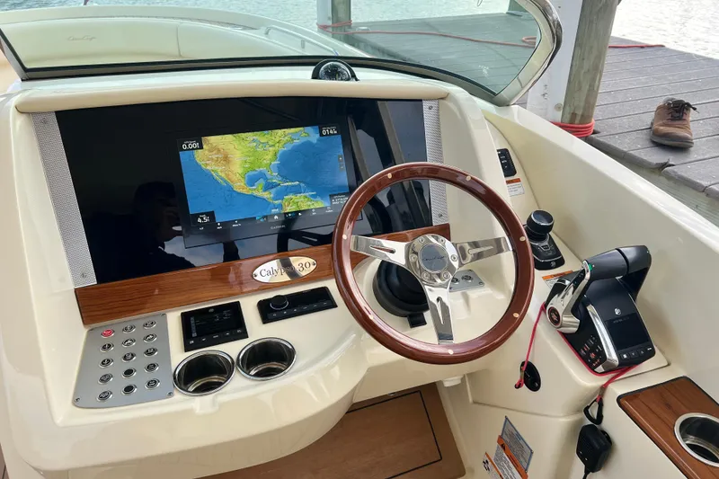 Slide: The Image of 2023 Chris-Craft Calypso 30 helm with navigation display and wooden steering wheel. - 15