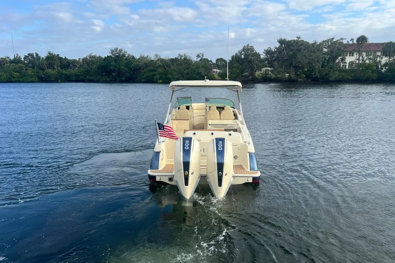 Slide: The Image of 2023 Chris-Craft Calypso 30 boat on water, rear view with American flag. - 2
