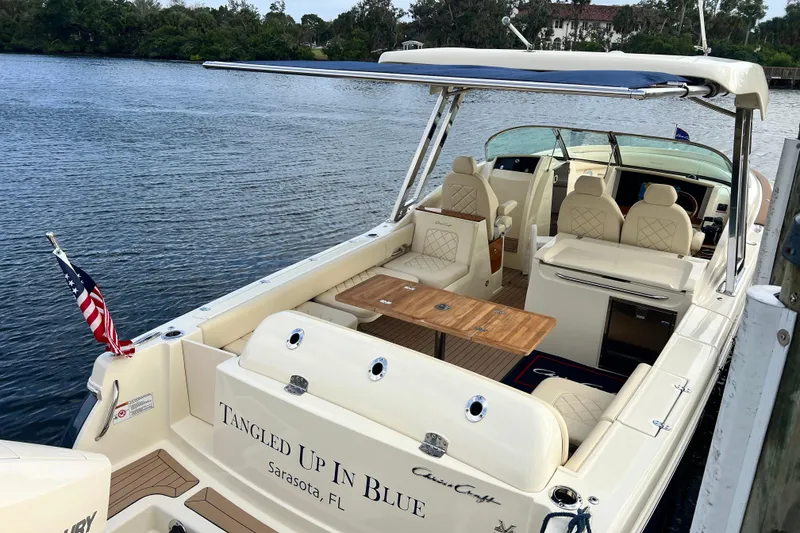Slide: The Image of 2023 Chris-Craft Calypso 30 boat docked, featuring elegant seating and wooden table. - 9