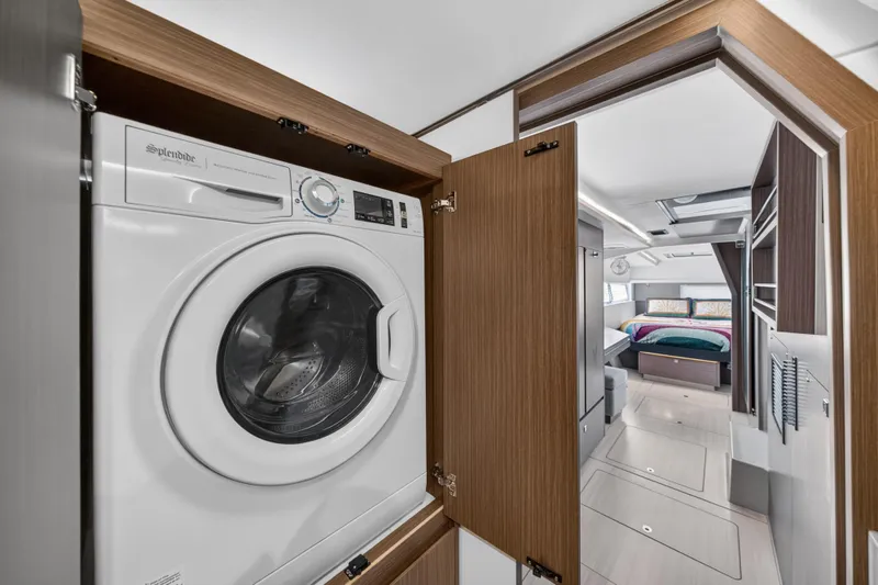 Slide: The Image of Laundry area with washer in 2024 Leopard 45 yacht interior, featuring modern wood cabinetry. - 115