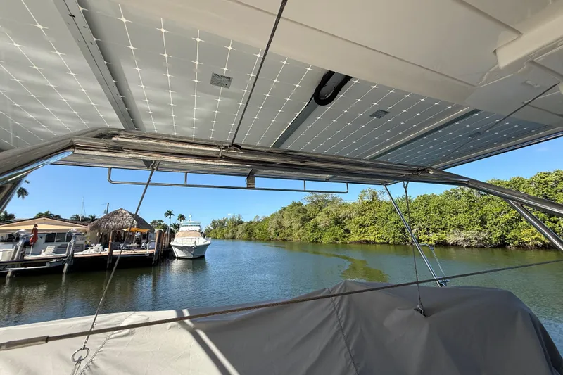 Slide: The Image of 2024 Leopard 45 catamaran with solar panels, docked near lush greenery and waterfront homes. - 34