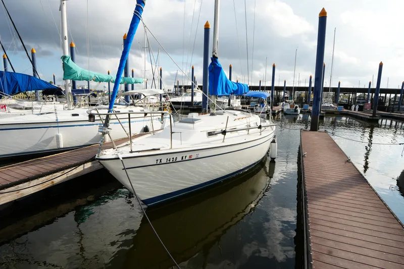 The Image of 1985 Pearson 303 sailboat docked at marina, surrounded by other boats. - 1