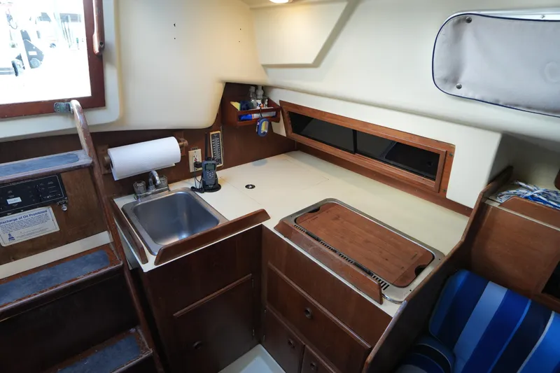 Slide: The Image of 1985 Pearson 303 yacht interior galley with sink, stove, and wooden cabinetry. - 21