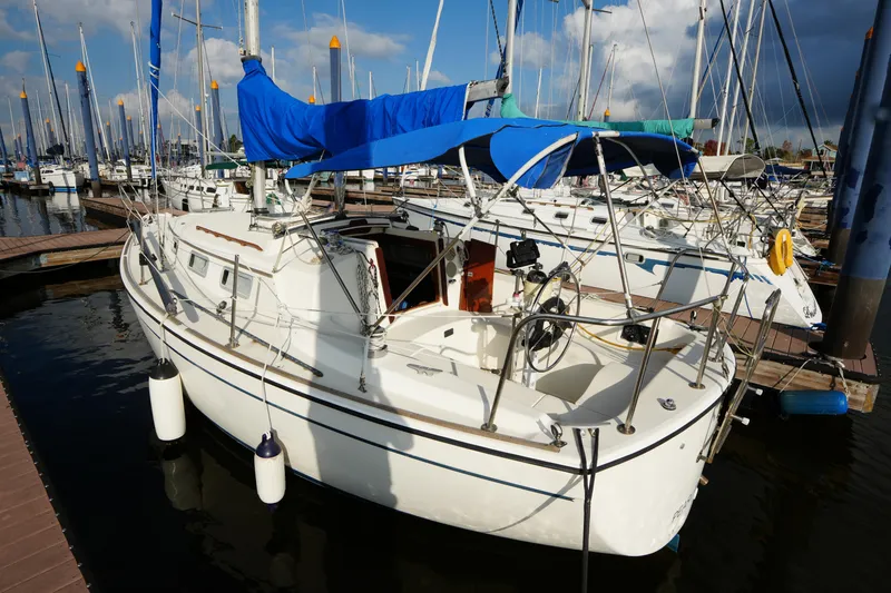 Slide: The Image of 1985 Pearson 303 sailboat docked at marina, featuring blue canopy and white hull. - 3