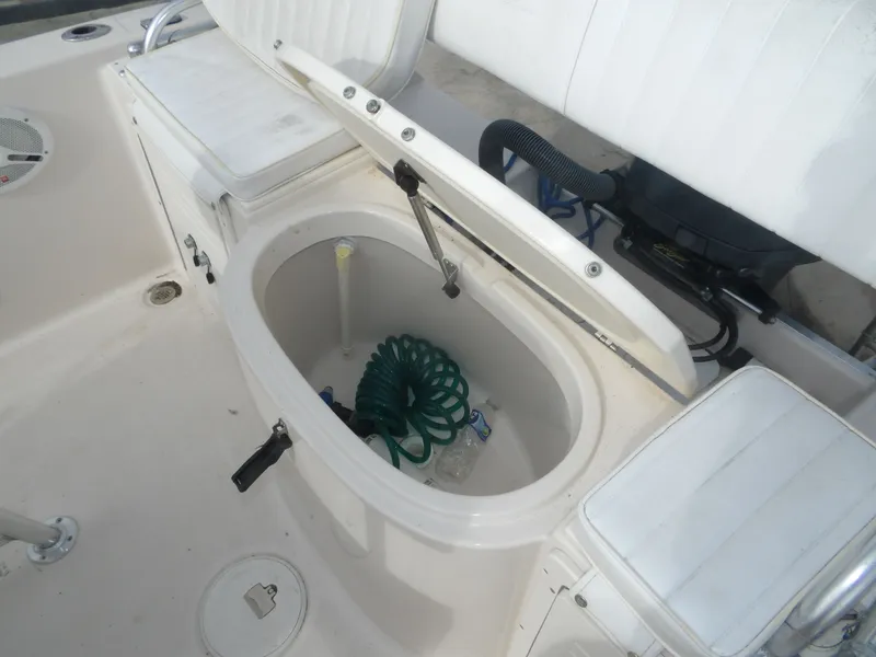 Slide: The Image of 2006 Cobia 214 Center Console with open storage compartment and hose. - 32