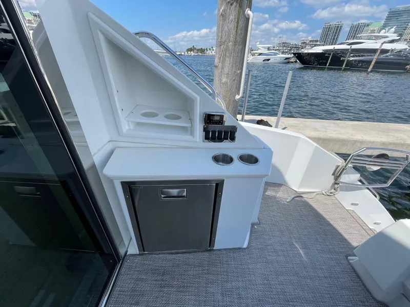 Slide: The Image of 2019 Cruisers 50 Cantius yacht deck with kitchenette and marina view. - 10