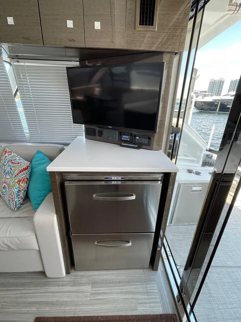 Slide: The Image of 2019 Cruisers 50 Cantius yacht interior with TV, stainless steel drawers, and waterfront view. - 13