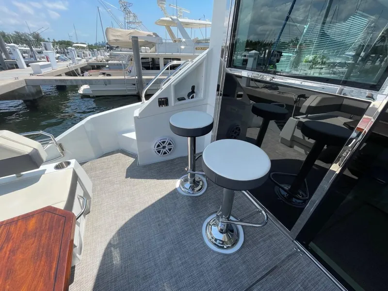 Slide: The Image of 2019 Cruisers 50 Cantius yacht deck with bar stools and marina view. - 9