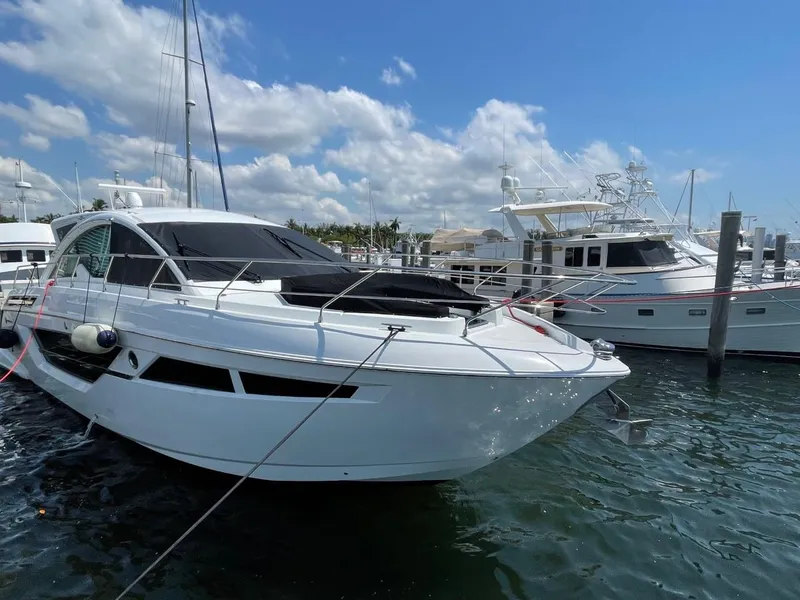 Slide: The Image of 2019 Cruisers 50 Cantius yacht docked in a sunny marina. - 1