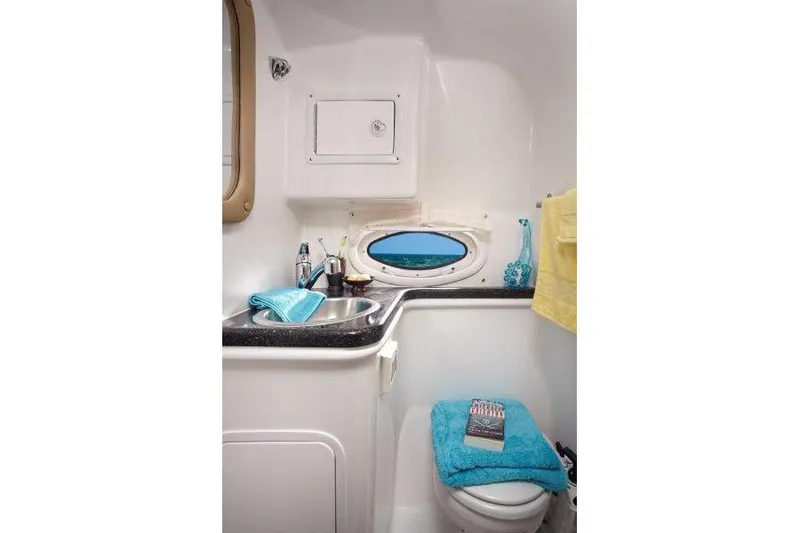 Slide: The Image of Manufacturer Provided Image: 2019 Rinker 290 EX boat bathroom with sink, toilet, and porthole window. - 10