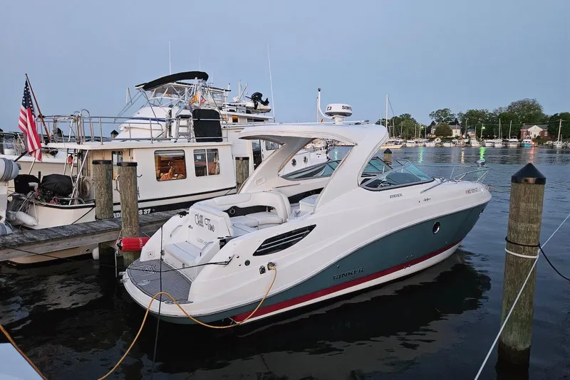 Slide: The Image of 2019 Rinker EX 290 boat docked at marina, calm water, evening setting. - 2