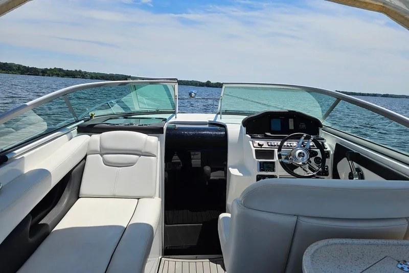 Slide: The Image of 2019 Rinker EX 290 boat interior with steering wheel, white seating, and lake view. - 4