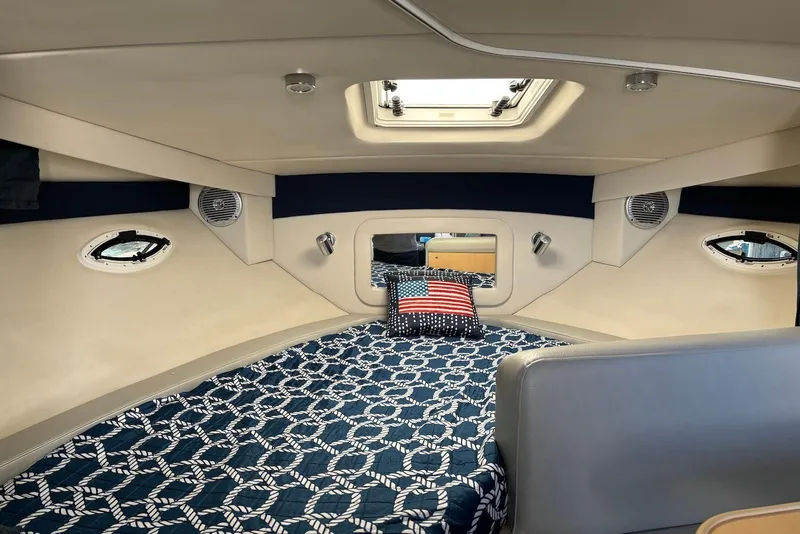 Slide: The Image of 2011 Bayliner 285 Cruiser interior with seating, wood flooring, and helm in a marina setting. - 4