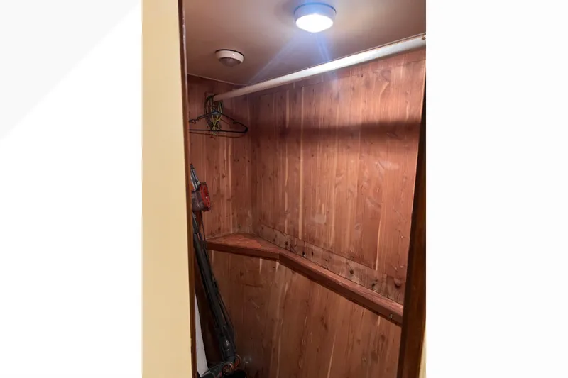 Slide: The Image of Wood-paneled closet interior on a 1999 Viking 60 CPMY yacht, featuring hangers and a vacuum. - 104