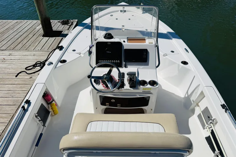 Slide: The Image of 2017 Sea Pro 208 Bay boat cockpit with steering wheel and controls, docked by wooden pier. - 17