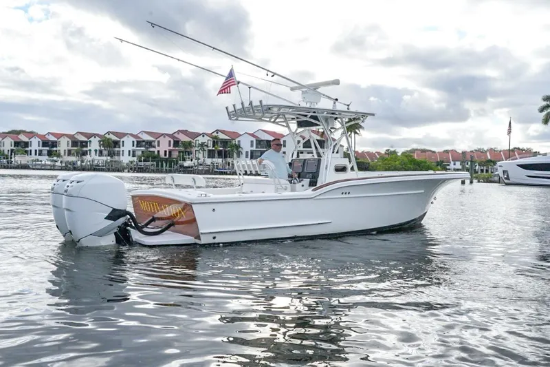 Slide: The Image of 2008 Buddy Davis 28 Center Console boat on water, with American flag, near waterfront homes. - 19