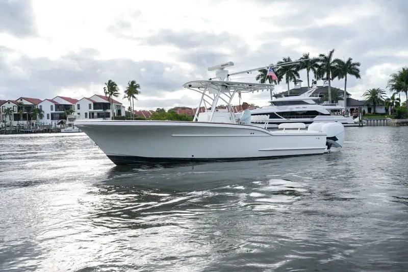 Slide: The Image of 2008 Buddy Davis 28 Center Console boat on water near waterfront homes and palm trees. - 2