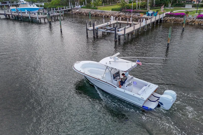 Slide: The Image of 2008 Buddy Davis 28 Center Console boat cruising near docks in a scenic waterfront setting. - 22