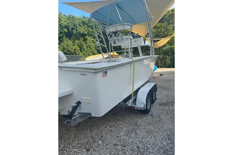 Slide: The Image of 2016 Rambo 27 boat on trailer, white hull, American flag sticker, parked on gravel. - 22