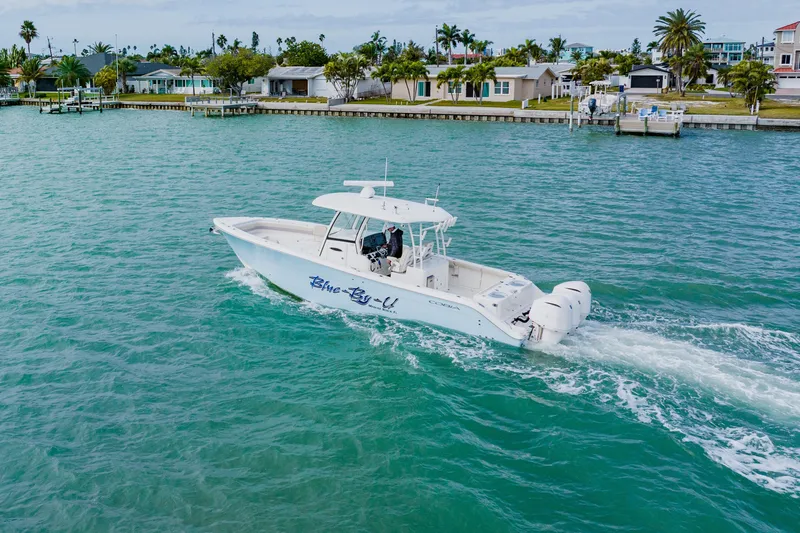 Slide: The Image of 2017 Cobia 344 Center Console boat cruising on turquoise water near coastal homes. - 26