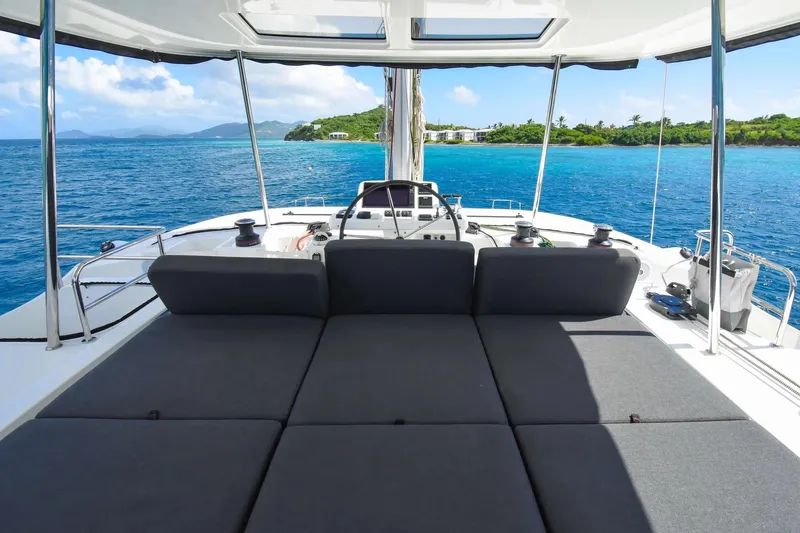 Slide: The Image of 2021 Lagoon 50 catamaran with spacious deck, overlooking serene blue waters and lush island. - 2