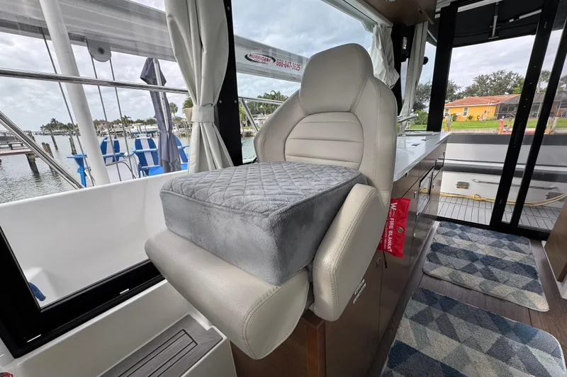 Slide: The Image of Interior of 2022 Jeanneau NC Weekender 1095 with cushioned seating and scenic marina view. - 12