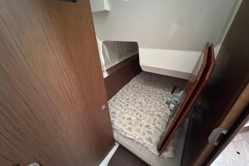 Slide: The Image of 2022 Jeanneau NC Weekender 1095 cabin interior with wooden finish and patterned bedding. - 17