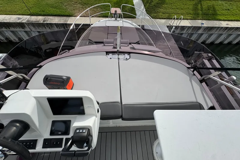 Slide: The Image of 2022 Jeanneau NC Weekender 1095 boat helm and deck view, docked by grassy shore. - 24