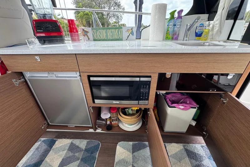 Slide: The Image of Kitchen area of 2022 Jeanneau NC Weekender 1095 with microwave and storage cabinets. - 9