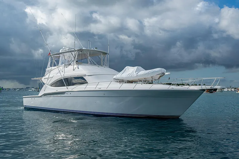 Slide: The Image of 2006 Bertram 630 Convertible yacht on calm waters under cloudy skies. - 11