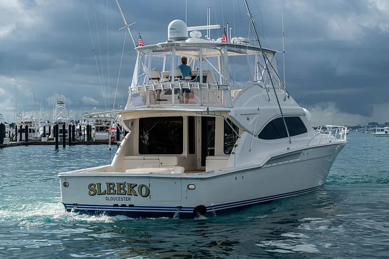 Slide: The Image of 2006 Bertram 630 Convertible yacht "SLEEKO" cruising in a marina under cloudy skies. - 13