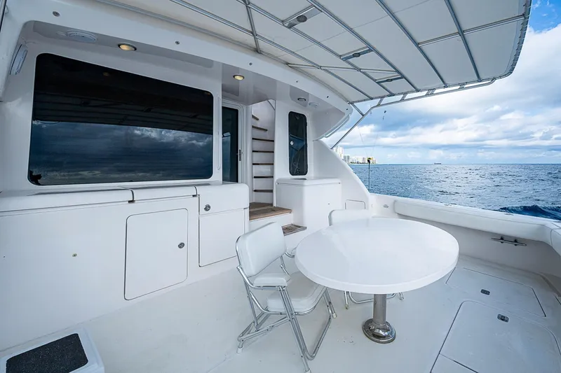 Slide: The Image of 2006 Bertram 630 Convertible yacht deck with ocean view, featuring white seating and table. - 14