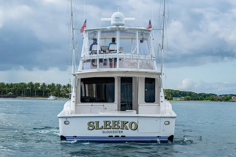 Slide: The Image of 2006 Bertram 630 Convertible yacht "SLEEKO" cruising near palm-lined shore. - 3