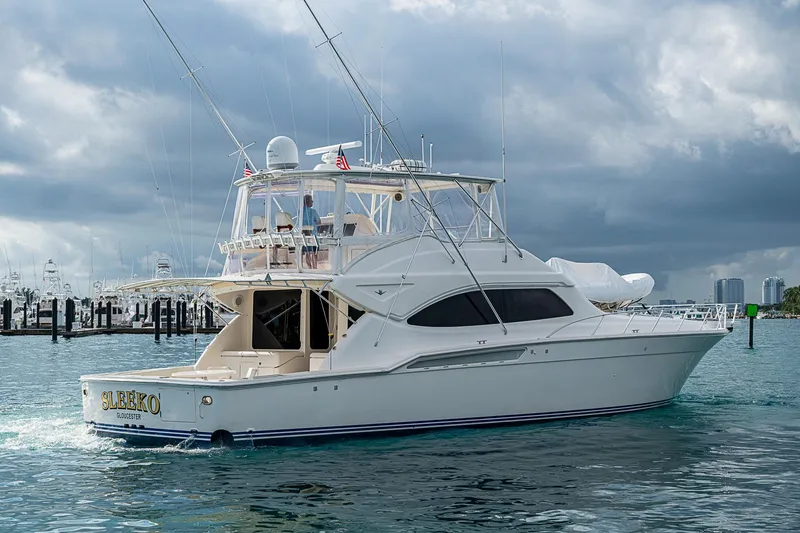 Slide: The Image of 2006 Bertram 630 Convertible yacht cruising in a marina under cloudy skies. - 4