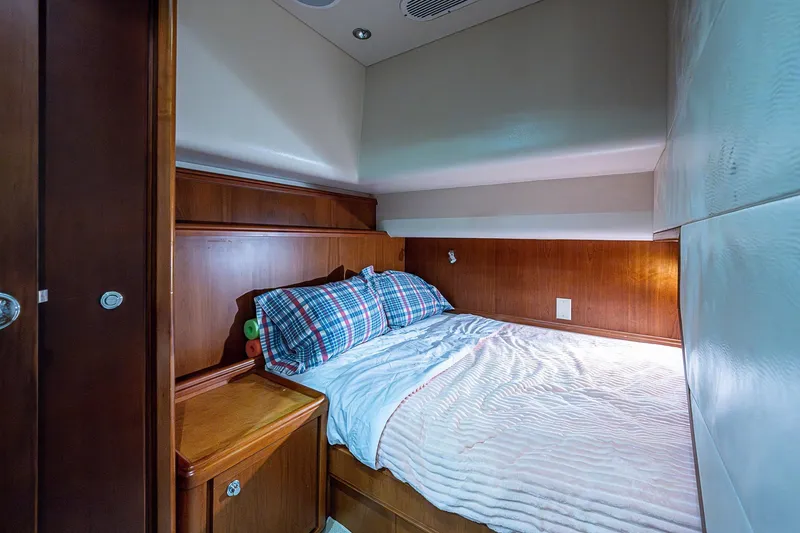 Slide: The Image of Cozy bedroom interior of 2006 Bertram 630 Convertible yacht with wood paneling and plaid bedding. - 48