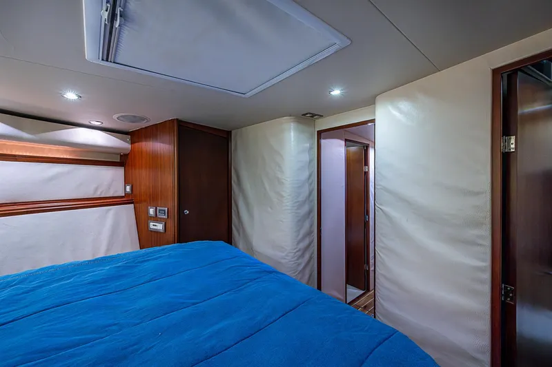 Slide: The Image of Interior cabin of 2006 Bertram 630 Convertible yacht with blue bedding and wood accents. - 65
