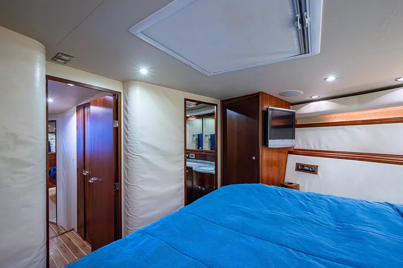 Slide: The Image of Luxurious interior of 2006 Bertram 630 Convertible yacht with blue bedding and wood accents. - 66