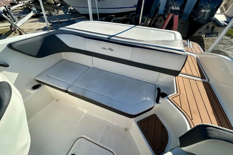 Slide: The Image of 2018 Sea Ray SPX 190 Outboard boat interior with cushioned seating and wood accents. - 13