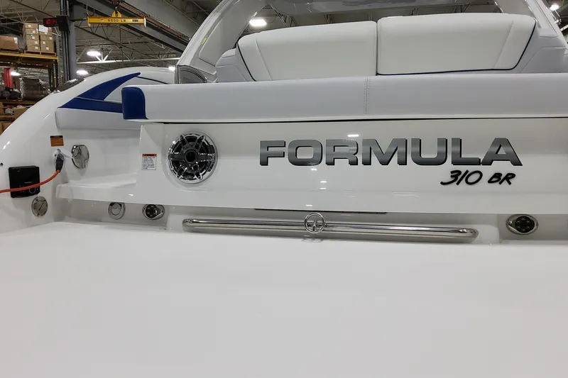 Slide: The Image of 2026 Formula 310 Bowrider I/O boat rear view in a showroom setting. - 12