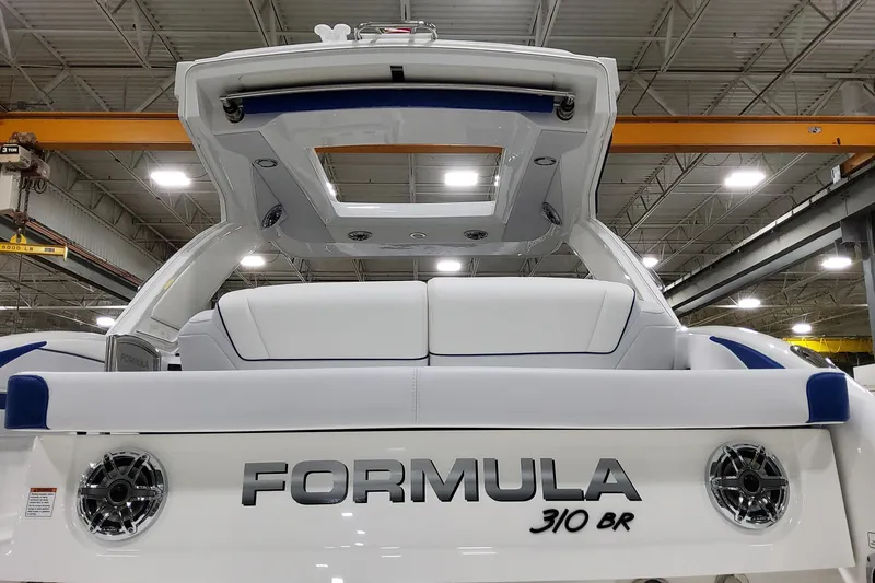 Slide: The Image of 2026 Formula 310 Bowrider I/O boat in a showroom, rear view with seating and speakers. - 13