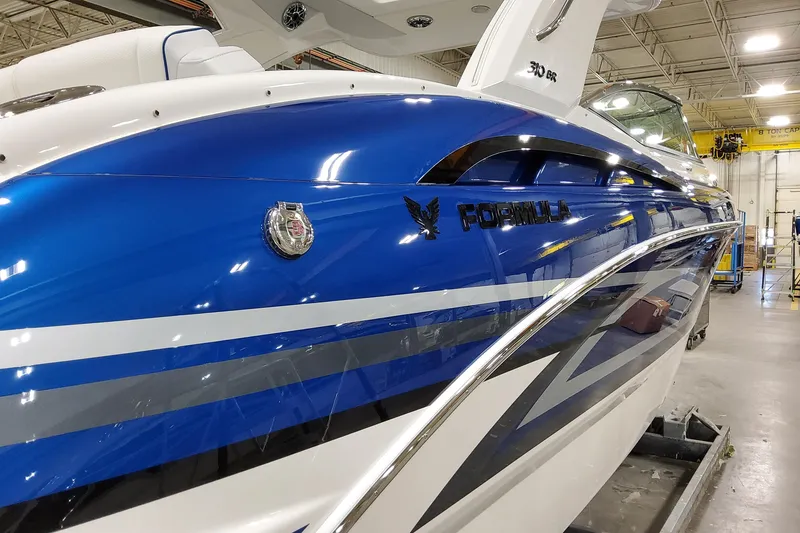 Slide: The Image of 2026 Formula 310 Bowrider I/O boat with sleek blue and white design in a showroom. - 4