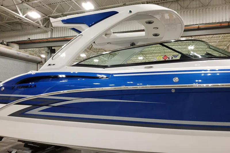 Slide: The Image of 2026 Formula 310 Bowrider I/O boat in showroom, featuring sleek blue and white design. - 6