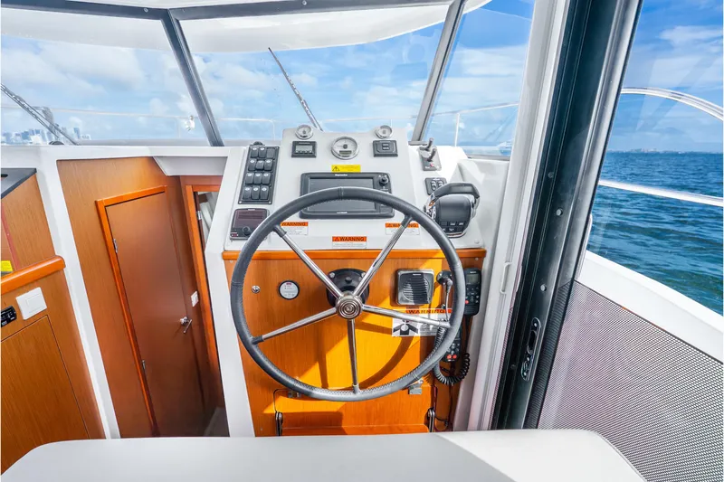 Slide: The Image of 2017 Beneteau Swift Trawler 30 helm with steering wheel and navigation controls. - 13
